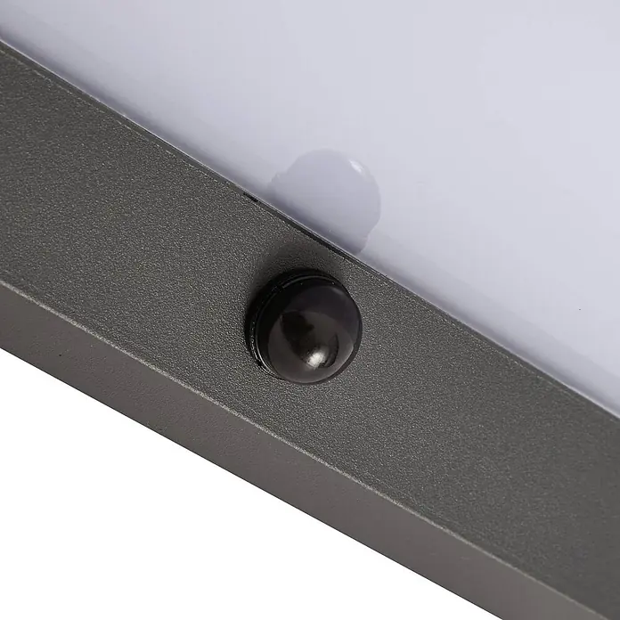 Lindby Außenwandleuchte Fando - alu / grau / zink, IP44 - Dunkelgrauer, texturierter Rahmen mit durchscheinender weißer Platte und schwarzem kugelförmigem Sensor.