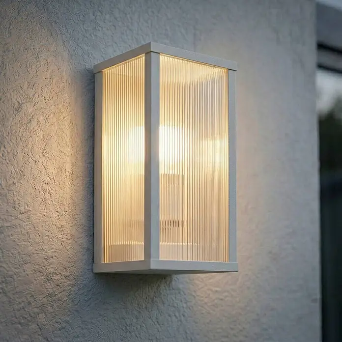 Lindby Außenwandleuchte Peldar - 13,5 x 14 x 26 cm, alu / grau / zink, IP44 - Rechteckige Außenwandleuchte mit hellgrauem Rahmen und geriffelten Glaspaneelen, an einer strukturierten Wand montiert und warmes Licht spendend.