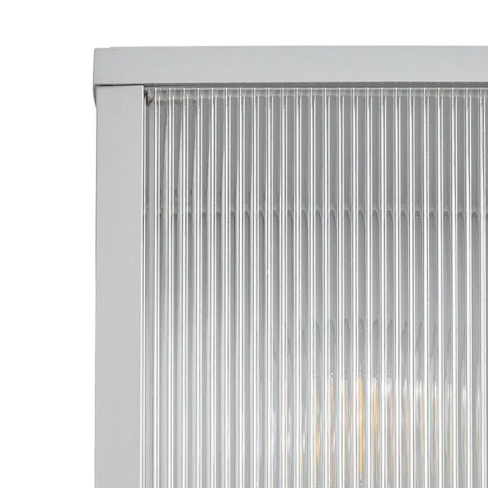 Lindby Außenwandleuchte Peldar - 13,5 x 14 x 26 cm, alu / grau / zink, IP44 - Nahaufnahme einer klaren, vertikal gerippten Glasplatte in einem hellgrauen Rahmen, mit durchscheinendem Licht.