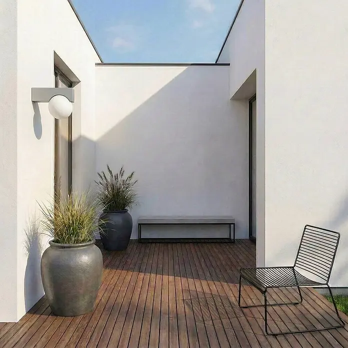 Lucande Außenwandleuchte Vijon - alu / grau / zink, IP44 - Moderne Terrasse mit schwarzem Lattenstuhl, grauer Bank, großen Topfpflanzen und weißer Kugelleuchte auf Holzdeck.