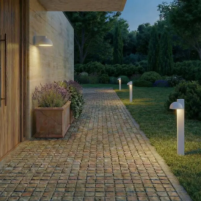 Lucande Außenwandleuchte Velira - alu / grau / zink, alu / grau / zink, IP54 - Moderne weiße Außenleuchten beleuchten einen Steinweg und Garten in der Dämmerung.