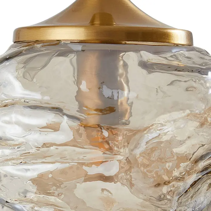 Lindby Pendelleuchte Piatra - L x B x H: 25 x 25 x 150 cm, creme / amber, amber, messing, G9 - Nahaufnahme einer Lampe mit goldfarbenem Metallsockel und strukturierter bernsteinfarbener Glasschirm.