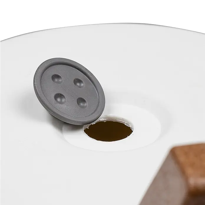 Siena Garden Pflanztopf OSLO PURE - Weiß, Kunststoff, Außenmaß (Ø x H): 47 x 26,5 cm - Grauer, knopfförmiger Stopfen mit vier Vertiefungen, teilweise in ein Loch auf einer weißen Oberfläche neben einem braunen Holzteil gesteckt.