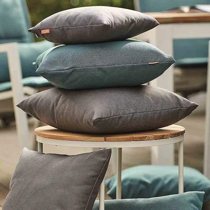 Siena Garden Kissen PRIME - 45 x 45 cm, Grau, Quadratisch - Texturierte Outdoor-Kissen in Grau und Blau, auf einem Holztisch für den Terrassengebrauch gestapelt.