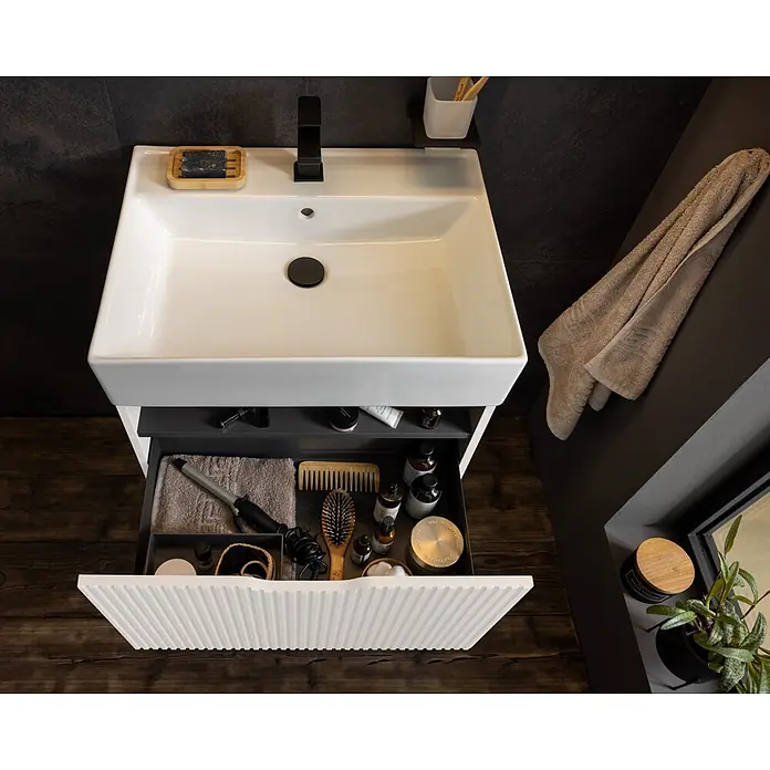 Camargue Vio Badmöbel-Set - Gesamtbreite Badmöbel: 61,5 cm, Weiß, Matt - Weißer Badunterschrank mit rechteckigem Waschbecken, schwarzem Wasserhahn und teilweise geöffneter gerippter Schublade mit Pflegeprodukten.