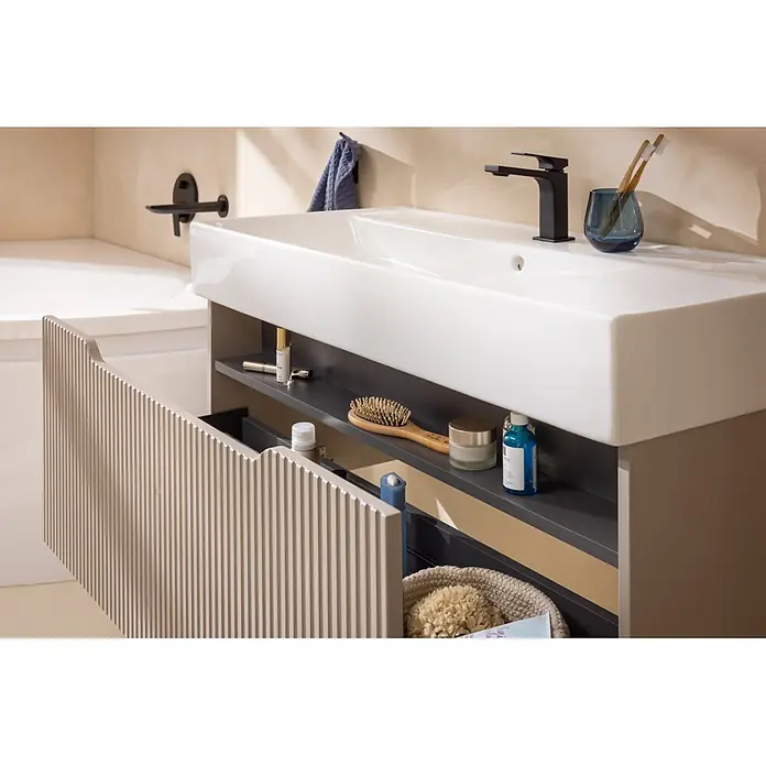 Camargue Vio Badmöbel-Set - Gesamtbreite Badmöbel: 100,6 cm, Kaschmir, Matt, DIN Anschlag: Links, Hahnloch: Mitte - Moderner Badezimmerschrank mit weißem Waschbecken, schwarzem Wasserhahn und geriffelter beiger Tür, die organisierte Toilettenartikel zeigt.