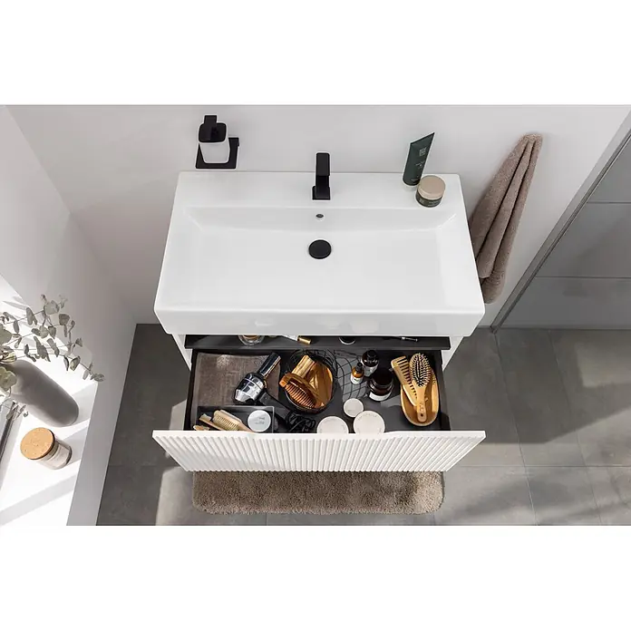 Camargue Vio Badmöbel-Set - Gesamtbreite Badmöbel: 81,5 cm, Weiß, Matt - Weißer Waschtisch mit schwarzem Wasserhahn und offener, geriffelter Schublade, die Badutensilien zeigt. Modernes Design.