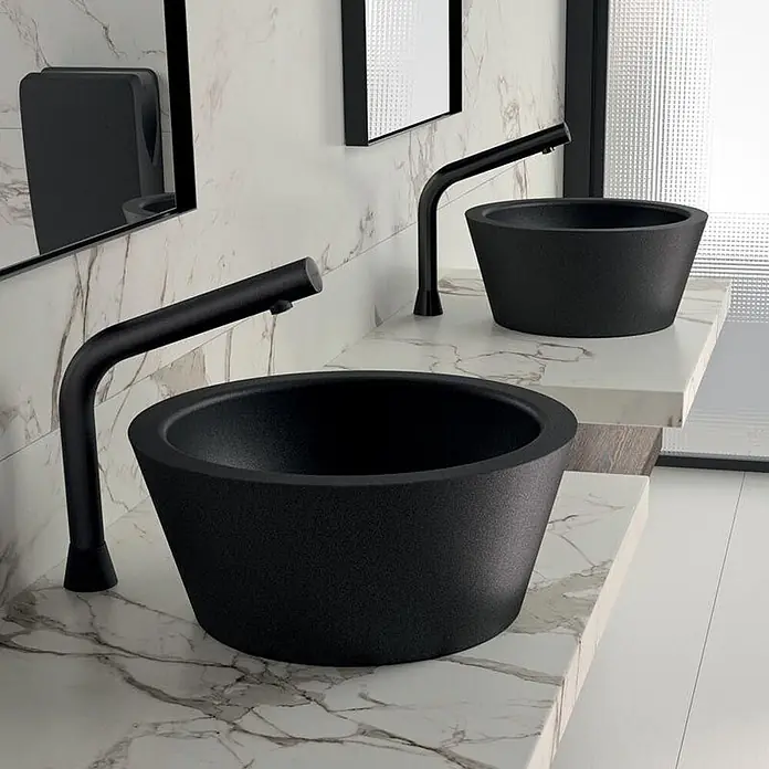 Delabie Aufsatzwaschbecken Delabie - 40,5 x 40,5 cm, Hahnloch: Ohne, Schwarz Matt - Zwei matte schwarze konische Aufsatzwaschbecken mit passenden gebogenen Armaturen auf Marmorwaschtischen.