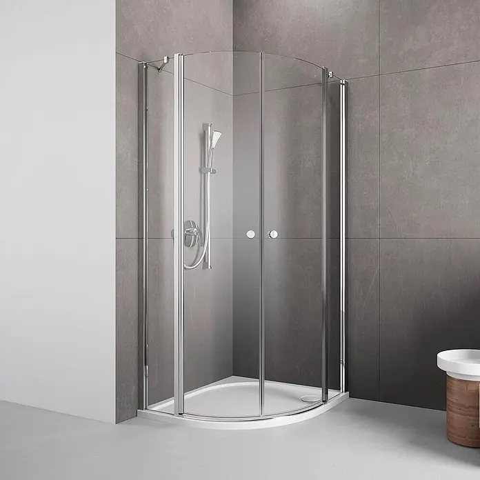 Puk Runddusche PUK - Chromoptik - Gebogene Glas-Duschkabine mit Chromprofilen und Schiebetüren auf einer weißen Duschwanne, mit Duschkopf.