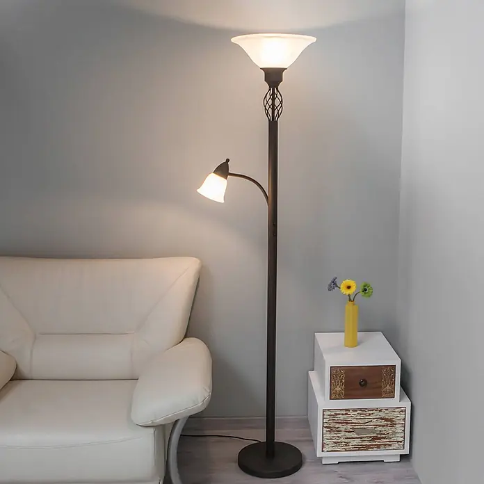Lucande LED-Deckenfluter Dunja - braun / rost - Bronzene Stehlampe mit Deckenfluter und Leselampe, neben einem cremefarbenen Sessel in einem Wohnbereich.