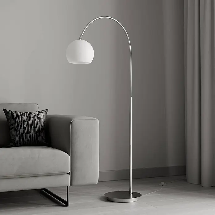 Lindby Stehleuchte Cynthia - alu / grau / zink, E27 - Moderne silberne Bogenstehlampe mit weißem Kugelschirm neben einem Sofa.