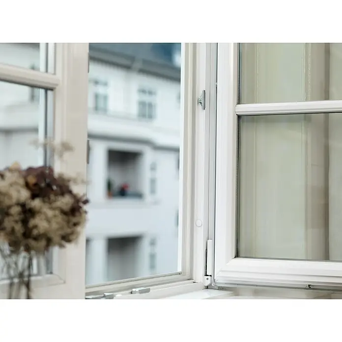 Tesa INSULATION Silikondichtung - Transparent, 6 m x 9 mm x 7 mm, Geeignet für: Spaltenbreiten 1 - 7 mm - Ein offenes weißes Fenster rahmt den Blick auf ein Gebäude, mit einer zweiten geschlossenen Fensterscheibe, die das moderne Design hervorhebt.