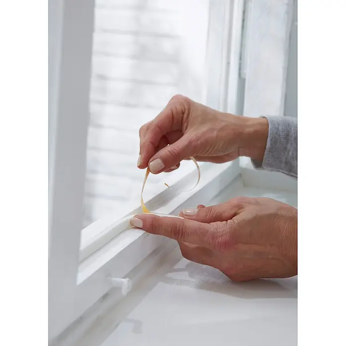 Tesa INSULATION Dichtungsband Schaumstoff M - Weiß, 6 m x 9 mm x 6 mm, Geeignet für: Spaltenbreiten 1 - 5 mm - Hände bringen weißes selbstklebendes Schaumdichtungsband am Fensterrahmen an.