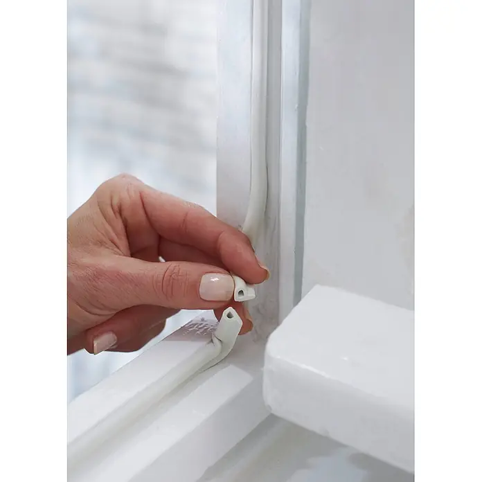 Tesa INSULATION Dichtungsband GUMMI L - L x B x H: 6 m x 9 mm x 5,5 mm, Weiß - Hand installiert weiße Dichtungsleiste in einen Fensterrahmen zur Isolierung.