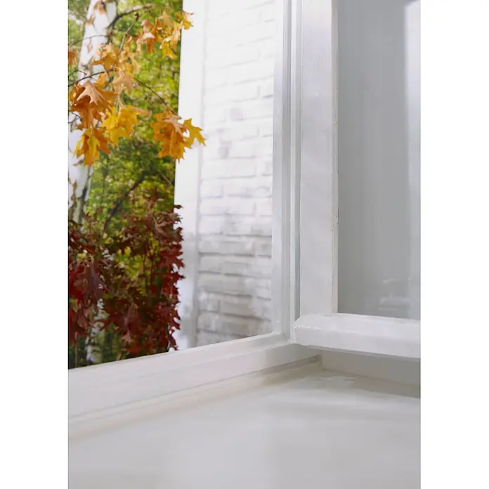 Tesa INSULATION Dichtungsband GUMMI L - Weiß, 10 m x 9 mm x 5,5 mm, Geeignet für: Spaltenbreiten 2 - 5 mm - Weißer Fensterrahmen, leicht geöffnet, mit Blick auf bunte Herbstblätter und einen grünen Wald.