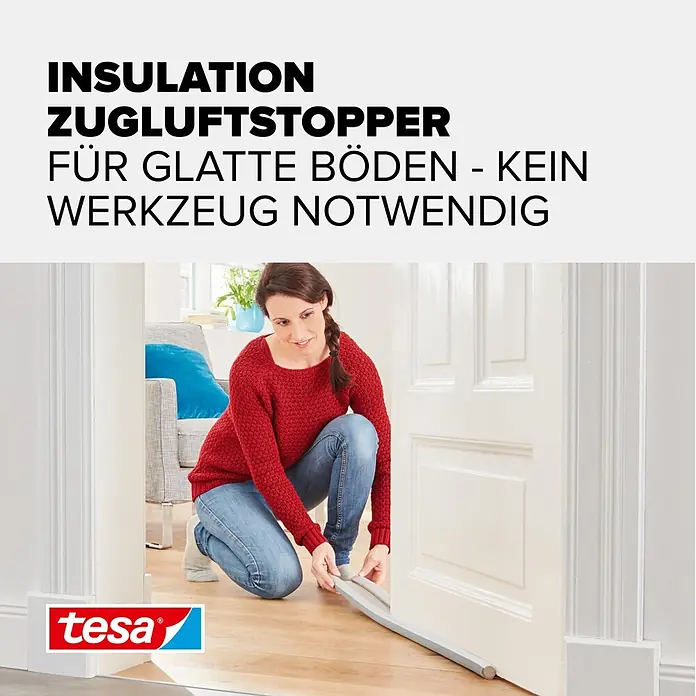 Tesa INSULATION Türbodendichtung Doppel-Dichtung - Weiß, 0,95 m x 25 mm, Geeignet für: Glatte Böden - Eine Frau installiert einen grauen Zugluftstopper unter einer Tür auf glattem Boden.