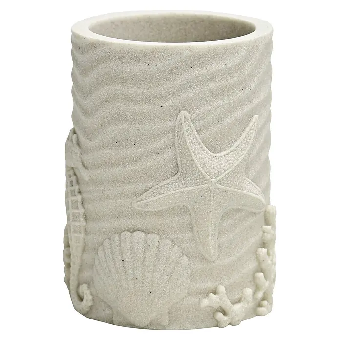 Camargue Koralle Zahnputzbecher - Polyresin, Sand - Sandfarbener zylindrischer Halter mit strukturierter Oberfläche und geprägten Seestern-, Muschel-, Seepferdchen- und Korallen-Verzierungen.