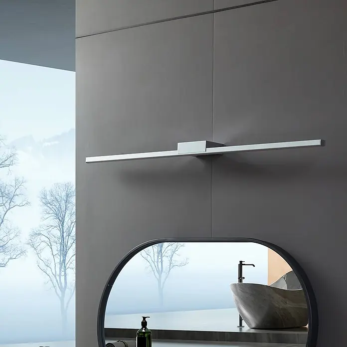 Lucande Wandleuchte Kivana - chrom / silber, chrom / silber - Silberne lineare LED-Spiegelleuchte über einem ovalen Spiegel in einem modernen Badezimmer.