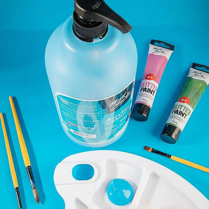 Mont Marte Acrylfarbe Signature - Ceruleanblau, 2.000 ml, Flasche mit Tropfpipette - Kunstbedarf: Eine große Flasche blauer Acrylfarbe, rosa und grüne Glitterfarben, eine weiße Palette mit blauer Farbe und Pinsel.