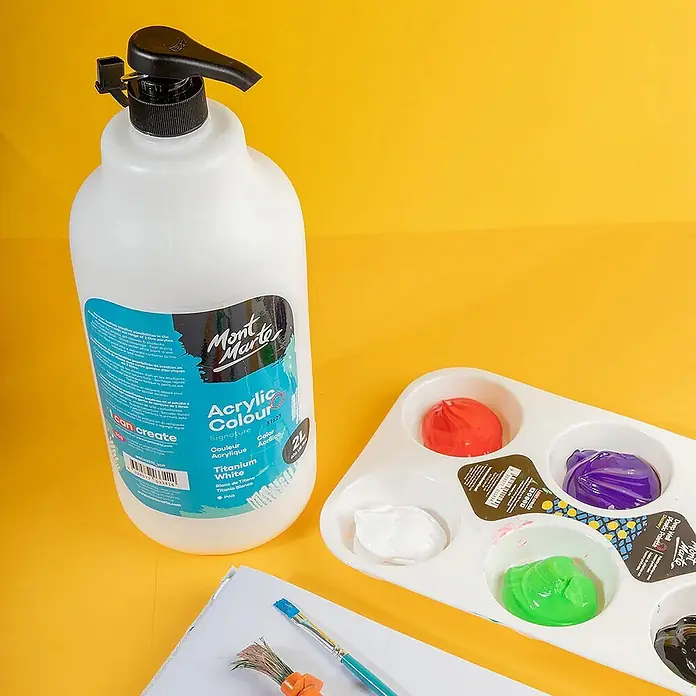 Mont Marte Acrylfarbe Signature - Titanweiß, 2.000 ml, Flasche mit Tropfpipette - Große weiße Mont Marte Acrylfarbflasche mit Pumpe, neben einer Farbpalette und einem Pinsel auf gelbem Hintergrund.