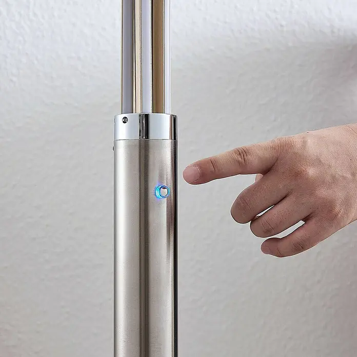 Lindby Stehleuchte Boba - Höhe: 185 cm, alu / grau / zink, alu / grau / zink - Säule aus gebürstetem Metall mit leuchtendem blauem Knopf, ein Finger nähert sich.