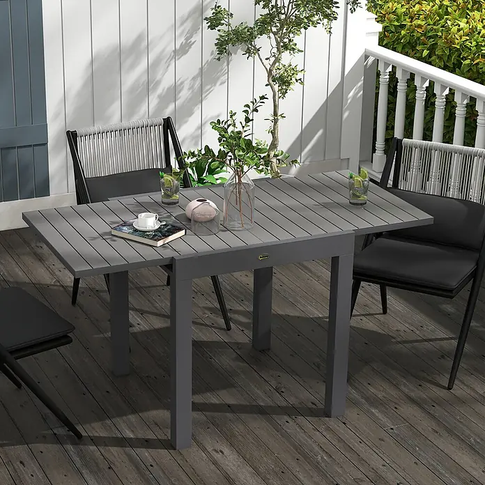 Outsunny Gartentisch - Aluminium, Quadratisch, Grau - Grauer Lamellen-Esstisch für den Außenbereich mit schwarzen Stühlen auf einer Terrasse, mit Getränken und einem Buch.