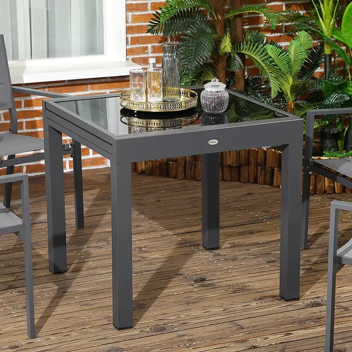 Outsunny Gartentisch - L x B x H: 80 x 80 x 75 cm, Epoxidiertes Metall, Aluminium, gehärtetes Glas, Rechteckig, Schwarz - Dunkelgrauer quadratischer Outdoor-Esstisch mit Glasplatte auf einer Holzterrasse, mit Tablett und Getränken.