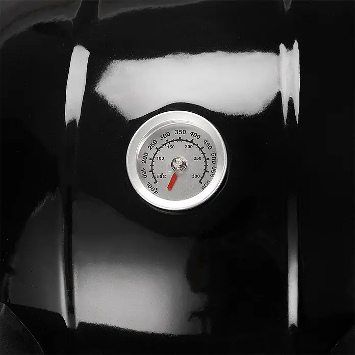 TAINO Holzkohlegrill NEO - Durchmesser Grillfläche: 54 cm, Schwarz - Nahaufnahme eines silberumrandeten Thermometers mit rotem Zeiger, das Temperaturen in Fahrenheit und Celsius anzeigt, eingebettet in einen glänzenden schwarzen Grilldeckel.