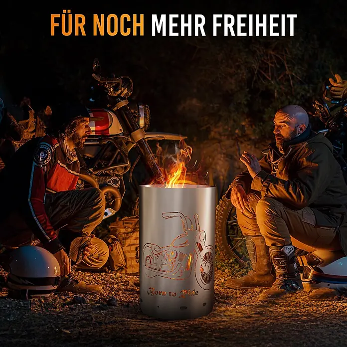 TiKo-Design Holzkohlegrill Feuertonne-Born to ride - Grau - Edelstahl-Feuerschale mit Motorrad-Ausschnittdesign, von Feuer beleuchtet, von zwei Männern auf einem Campingplatz genutzt.
