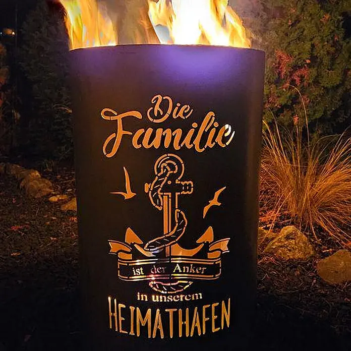 TiKo-Design Holzkohlegrill Feuertonne-Familie -  - Schwarzes Metall-Feuerfass mit beleuchtetem Anker und deutschem Textausschnitt, hell brennend im Freien.
