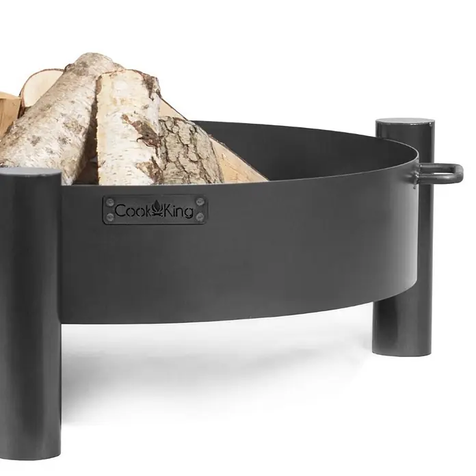 Bene on Fire Holzkohlegrill Minnesota - Schwarz - Runde schwarze Metall-Feuerschale mit Beinen und Cook King Logo, gefüllt mit Brennholz.
