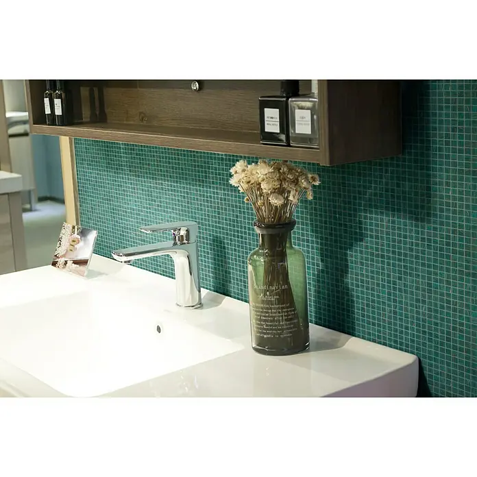 Mosaikfliese Goldstar GM GS 454749 - 30,5 x 30,5 cm, Türkis, Glänzend - Nahaufnahme eines modernen Badezimmers mit weißem Waschbecken, Armatur und Dekoration vor einer grünen Mosaikwand.