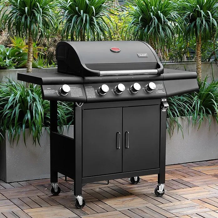 TAINO Gasgrill RED 4+1 - Anzahl Brenner: 4 Stk. - Schwarzer Gasgrill aus Metall mit mehreren Brennern, Seitenablagen und Schrank, auf Rollen, auf einer Holzterrasse.