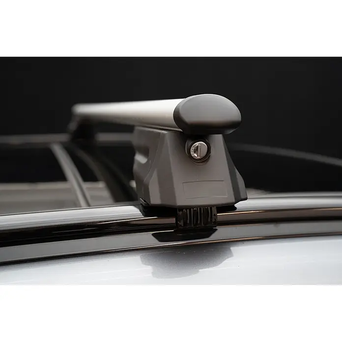 Fischer Baca Crossline XL - Capacidad de carga: 90 kg, L x An x Al: 15 x 131 x 10 cm - Primer plano de una barra transversal de techo de coche plateada con un pie de montaje gris oscuro y cerradura visible, fijada a un techo de vehículo plateado.