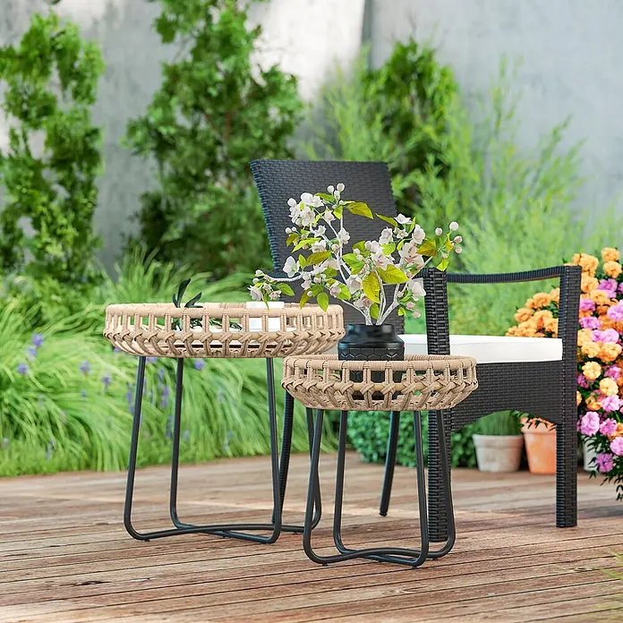 Outsunny Garten-Beistelltisch - L x B x H: 56 x 56 x 55 cm, Braun - Zwei Beistelltische zum Ineinanderschieben, mit Rattan-Tischplatten und schwarzen Metallbeinen, auf einer Außenterrasse.