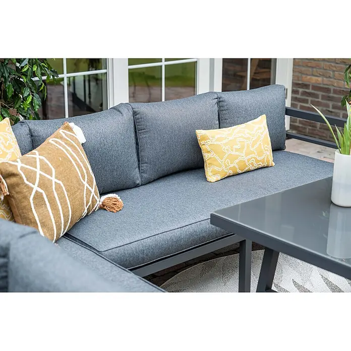 Garden Impressions Loungemöbel-Set Bleco II - 4 -tlg., Aluminium, Anthrazit/Schwarz - Graues Outdoor-Ecksofa mit grauen Stoffpolstern und gelben sowie braunen Zierkissen, auf einer Terrasse neben einem passenden Tisch.