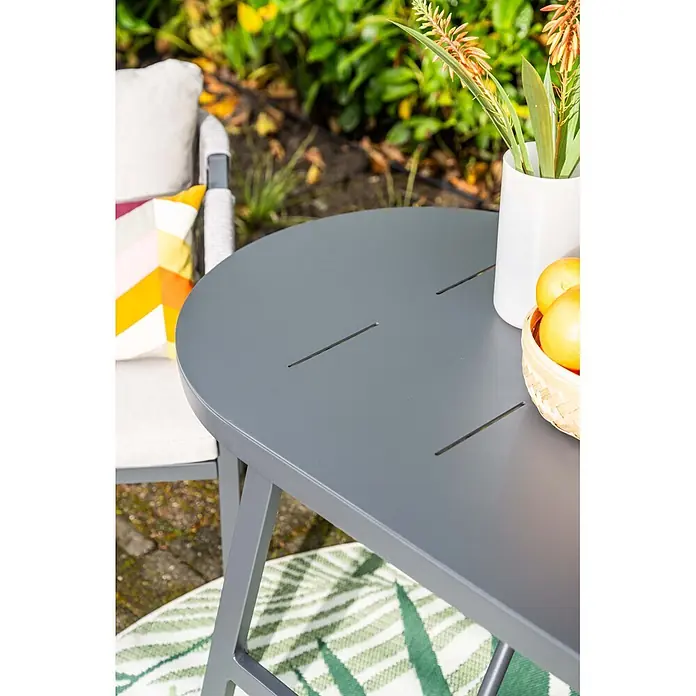 Garden Impressions Balkonmöbel-Set Terni - 3 -tlg., Aluminium, Schwarz - Grauer ovaler Gartentisch mit geschlitzter Metallplatte, neben einem Stuhl im Garten platziert.