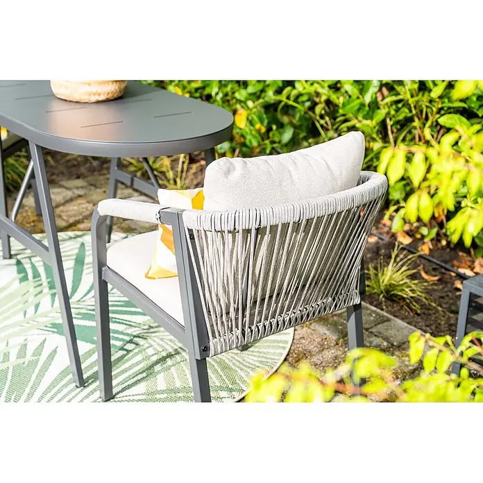 Garden Impressions Balkonmöbel-Set Terni - 3 -tlg., Aluminium, Schwarz - Grauer Outdoor-Stuhl mit geflochtener Rückenlehne und Armlehnen, Kissen, neben passendem Tisch auf der Terrasse.