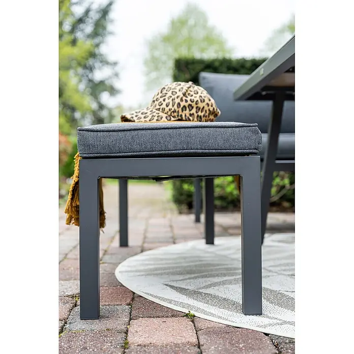Garden Impressions Loungemöbel-Set Bleco II - 4 -tlg., Aluminium, Anthrazit/Schwarz - Dunkelgraue Gartenbank mit grauem Stoffkissen und gelbem Überwurf auf einer Terrasse mit Teppich.