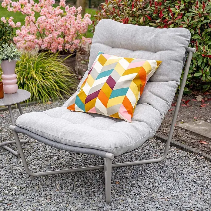 Garden Impressions Loungemöbel-Set Danzig - 3 -tlg., Aluminium, Polyester, Taupe - Grauer Outdoor-Loungesessel mit weichen Polstern und einem bunten Kissen, auf Kies in einem Garten stehend.