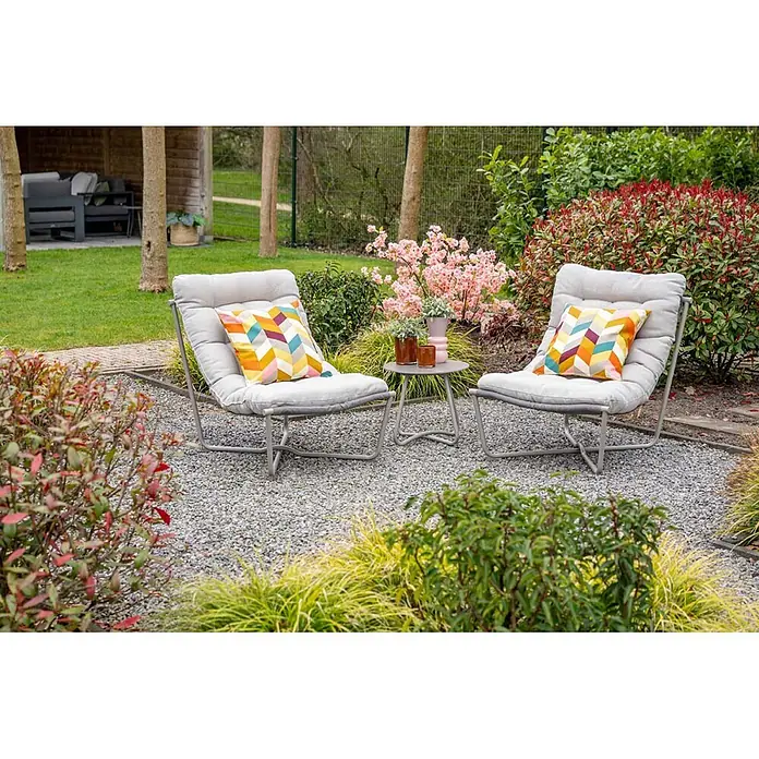 Garden Impressions Loungemöbel-Set Danzig - 3 -tlg., Aluminium, Polyester, Taupe - Zwei hellgraue Gartenstühle mit farbigen geometrischen Kissen und ein kleiner grauer Beistelltisch auf Kies.