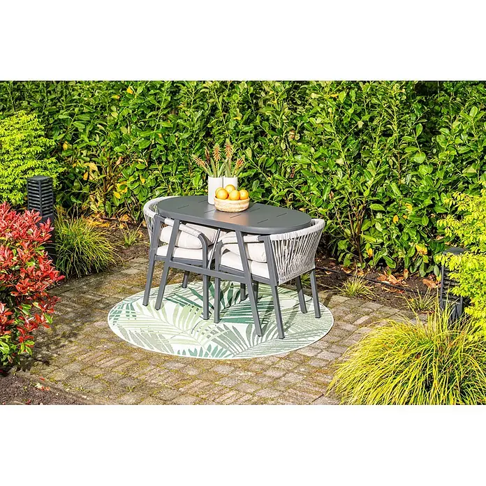 Garden Impressions Balkonmöbel-Set Terni - 3 -tlg., Aluminium, Schwarz - Dunkelgrauer Gartentisch und hellgraue Flechtstühle mit Kissen auf einem gemusterten Teppich im Garten.