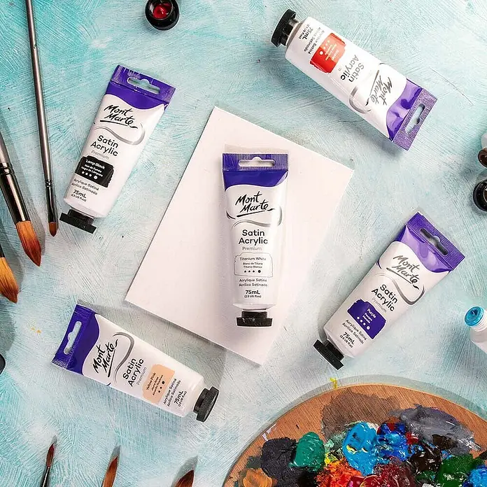 Mont Marte Acrylfarbe Premium - Titanweiß, 75 ml, Tube - Mont Marte Satin Acrylfarben-Tuben in verschiedenen Farben, Pinsel und eine Farbpalette, für eine Malsitzung arrangiert.