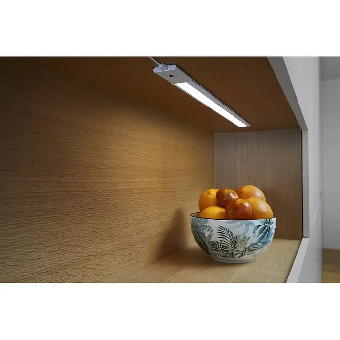 Osram LED-Unterbauleuchte Slim - L x B x H: 30 x 3,76 x 0,8 cm, Lichtfarbe: Warmweiß, 220 V - 240 V - Weiße LED-Unterbauleuchte beleuchtet ein Holzregal und eine Schale Orangen.