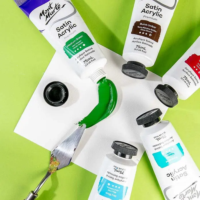 Mont Marte Acrylfarbe Premium - Mittelgrün, 75 ml, Tube - Mont Marte Satin Acrylfarben-Tuben in verschiedenen Farben, mit leuchtendem Mittelgrün auf einer weißen Fläche neben einem Spachtel.