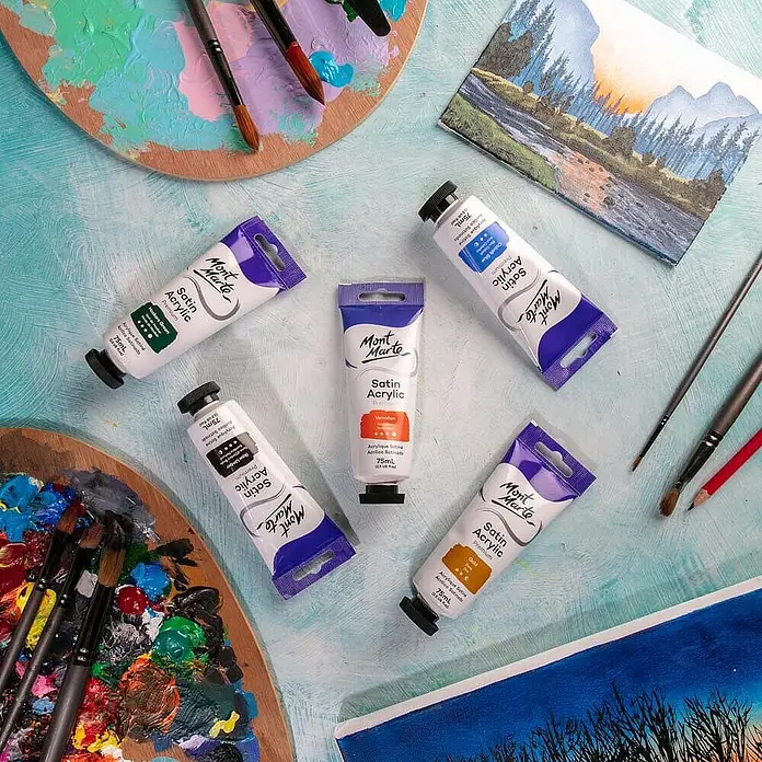 Mont Marte Acrylfarbe Premium - Zinnoberrot, 75 ml, Tube - Mont Marte Satin Acrylfarben in Tuben, umgeben von Künstlerpaletten, Pinseln und Gemälden.