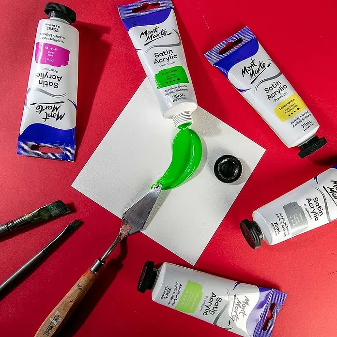 Mont Marte Acrylfarbe Premium - Hellgrün, 75 ml, Tube - Mont Marte Satin Acrylfarbtuben in verschiedenen Farben, ein Spachtel und Pinsel, mit grüner Farbe auf eine weiße Fläche gedrückt.