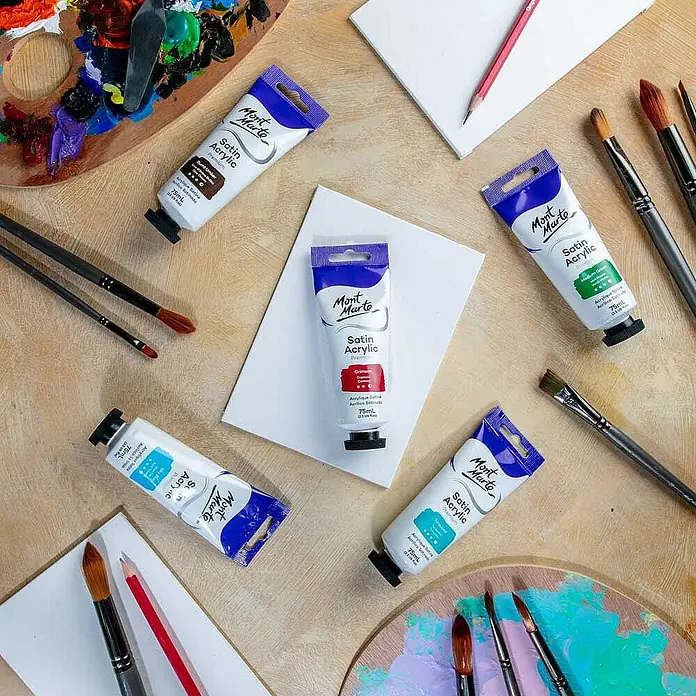 Mont Marte Acrylfarbe Premium - Karminrot, 75 ml, Tube - Mehrere Tuben Mont Marte Satin Acrylfarben sind mit Pinseln, einer Palette und kleinen Leinwänden für die Malerei angeordnet.