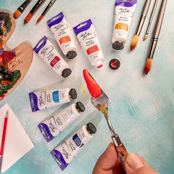 Mont Marte Acrylfarbe Premium - Brillantrot, 75 ml, Tube - Mont Marte Satin Acrylfarben-Tuben, Pinsel und ein Spachtel mit roter Farbe, bereit zum Malen.