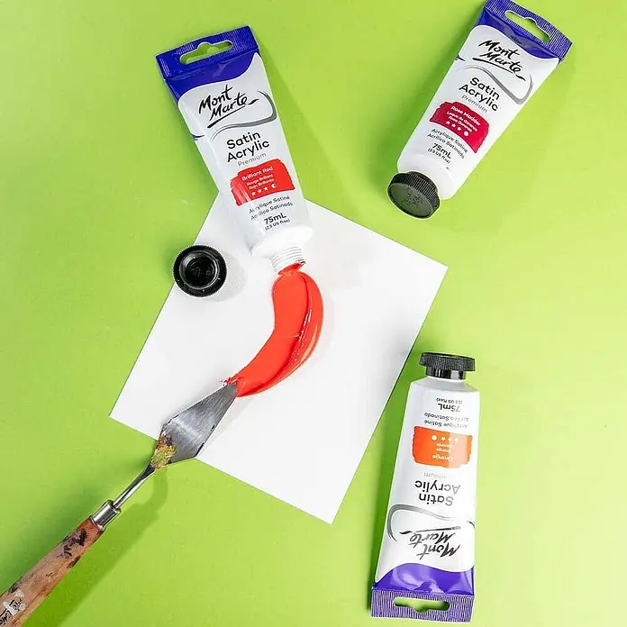 Mont Marte Acrylfarbe Premium - Brillantrot, 75 ml, Tube - Mont Marte Satin Acrylfarben in Rot, Rose Madder und Orange. Rote Farbe auf Papier mit Spachtel verteilt.